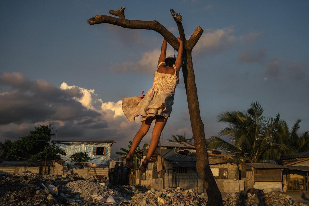 08 maart 2018: Photo and words by @hannahreyesmorales (Hannah Reyes Morales) | A Filipino girl, fondly called Puti by loved ones, climbs a tree branch in Tondo, home to hundreds of thousands of shanty dwellers. 'My dream is to become queen,' she proudly declares, in Tagalog. She tells me this is her favorite dress. 'It is beautiful when my papa washes it.' Her father collects coal for a living. 
This International Women's Day, my greatest hope is for the future of girls like Puti, whose dreams are boundless but whose opportunities are sparse. I know she will craft a life with the little she's been given, but today I am thinking about the greater heights she can climb if more opportunities were available to her. Happy Women's Day, everyone - there is so much to hope for, and so much work yet to be done. 
#PressforProgress #InternationalWomensDay #IWD2018 #WomensHistoryMonth #NatGeoWomen 
